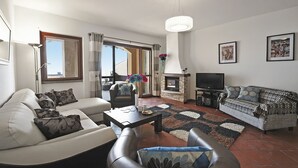 A living room with a sofa, armchairs, a coffee table, a fireplace, and a television. - Bellavista Grande (Menaggio)