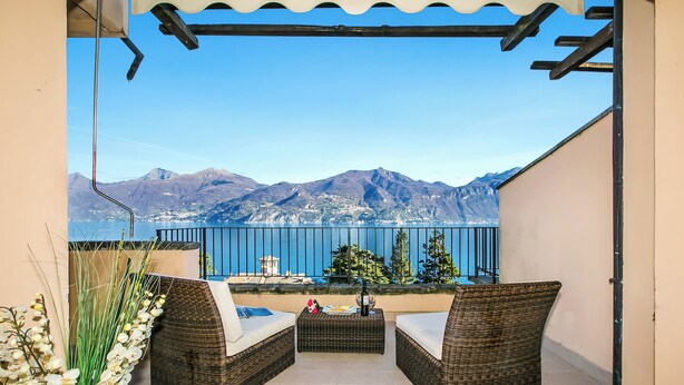 A balcony with wicker furniture, a small table, and a vase of flowers. - Bellavista Grande (Menaggio)