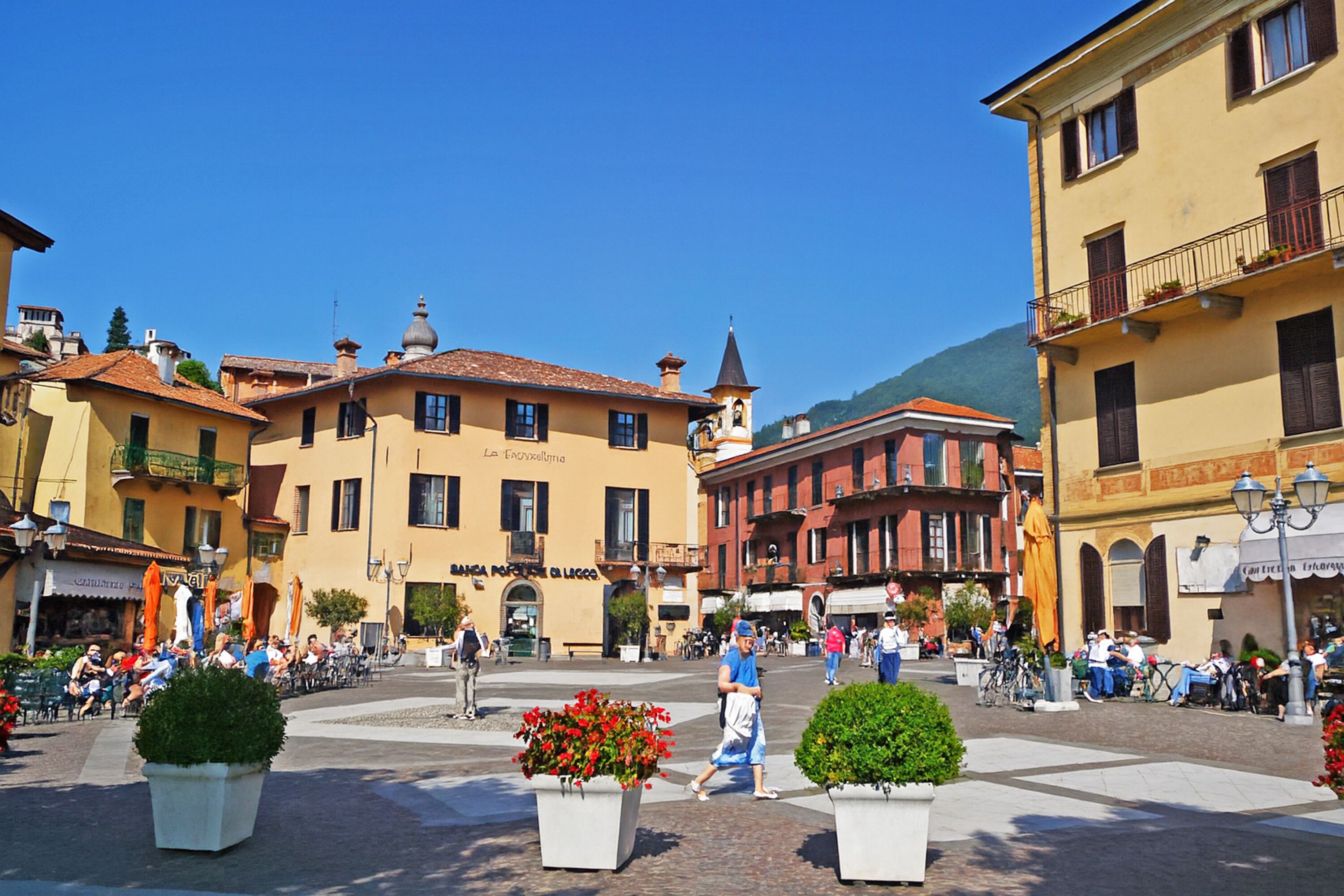 A square with buildings, outdoor seating, and potted plants.
