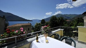 A balcony with a table set for two, overlooking a lake and mountains. - Residenza Bel Sit - Apt. 6 (Domaso)