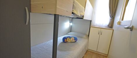 A bunk bed with a small desk and a window with curtains.