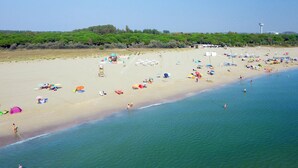 A beach with umbrellas, sun loungers, and people enjoying the water. - TopCamp in Union Lido (Cavallino-Treporti)