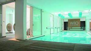 A modern indoor pool area with glass walls and a clear view of the adjacent leisure building labeled 'W10'. - TopCamp in Union Lido (Cavallino-Treporti)