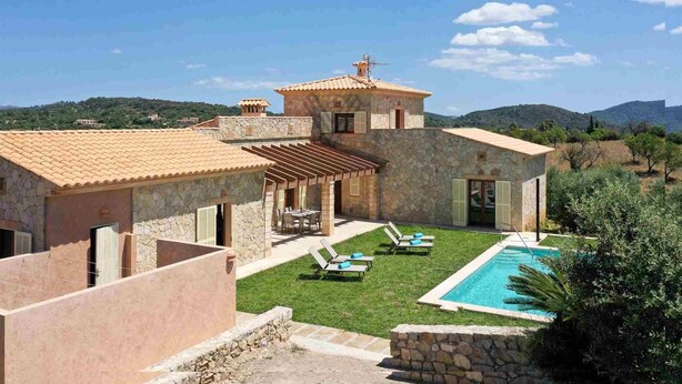 A stone villa with a swimming pool, outdoor seating, and a view of the surrounding hills.