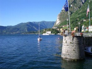A coastal scene with a sailboat on the water, a stone tower, and flags.