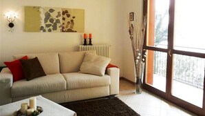 Ein Wohnzimmer mit Sofa, Couchtisch mit Kerzen, Heizkörper und großem Fenster mit Ausblick.