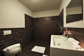 A modern bathroom with a white toilet, a sink, and a shower area.