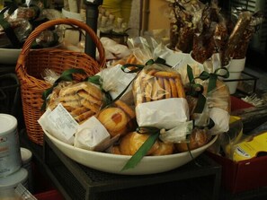 Un saladier rempli de diverses viennoiseries et pâtisseries, dont du pain, est présenté sur une table.