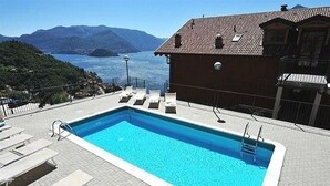 Ein Pool mit Liegestühlen und Blick auf einen See und Berge.