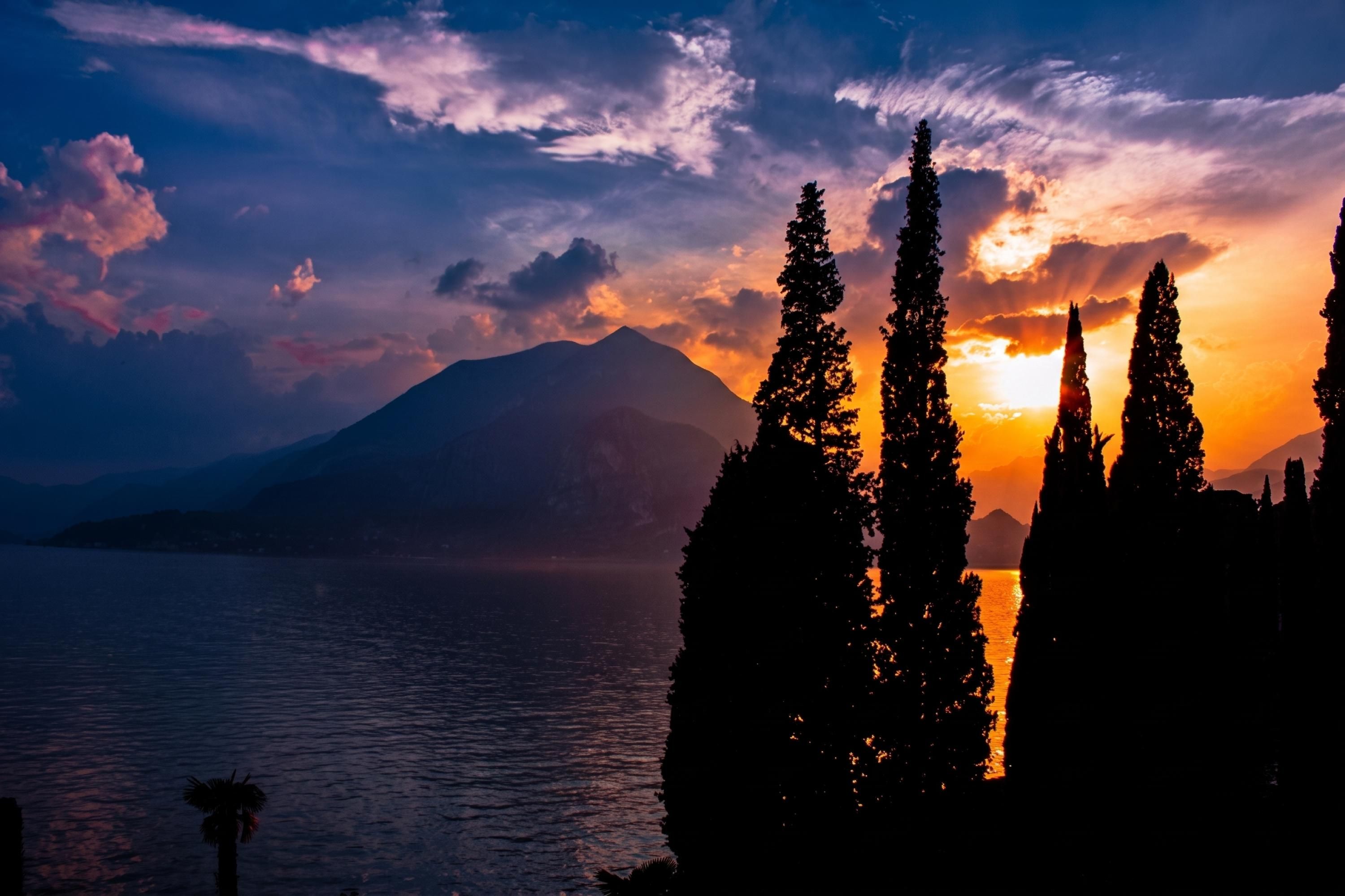 A mountain silhouette, a sunset, and a body of water.