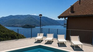 A swimming pool with lounge chairs and a view of a lake and mountains.