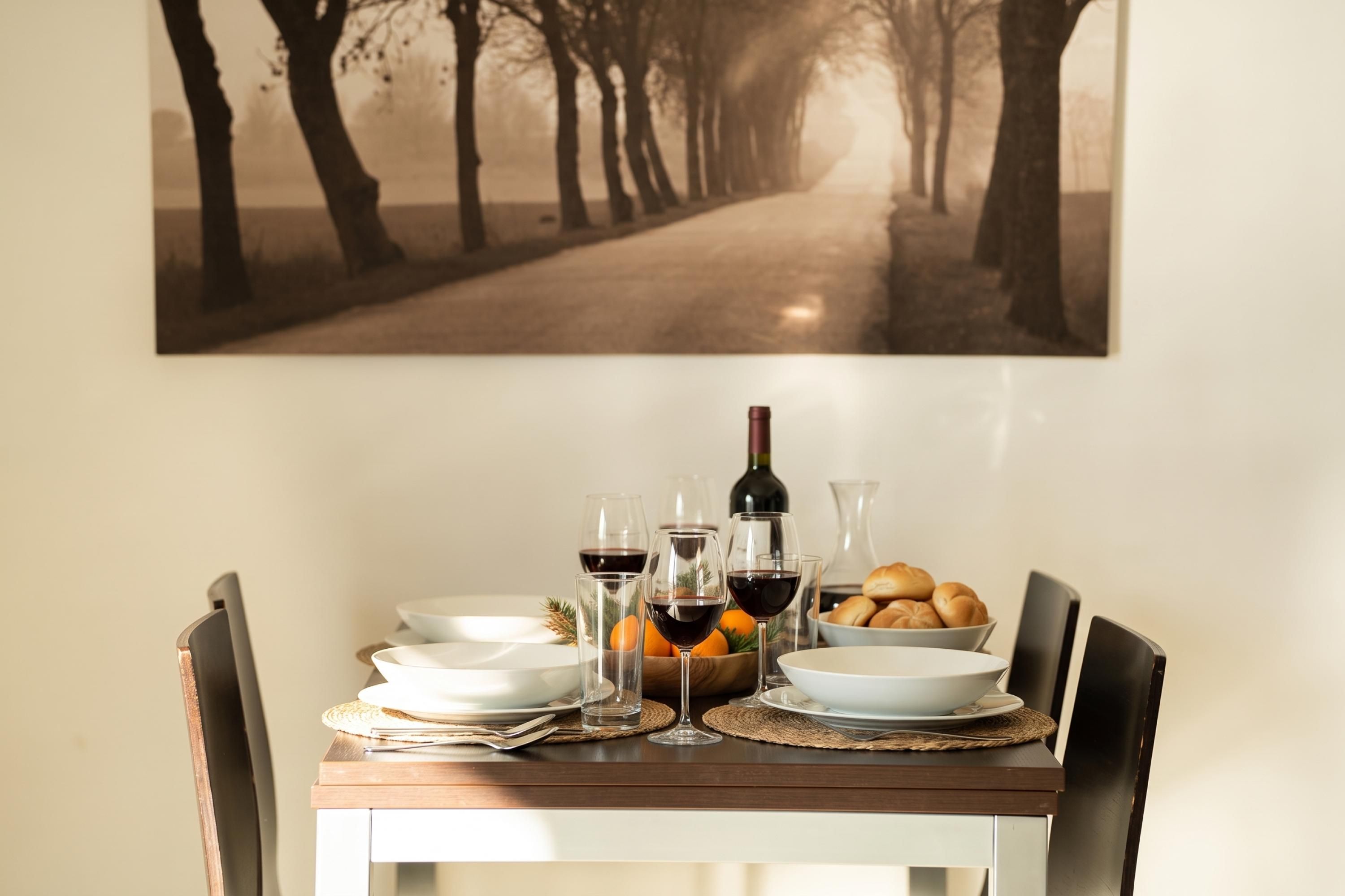 A dining table set with plates, glasses, a bottle, and bread.