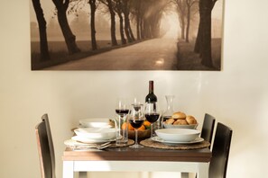 A dining table set with plates, glasses, a bottle, and bread.