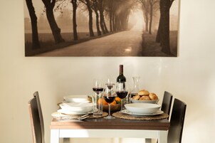 A dining table set with plates, glasses, a bottle, and bread.