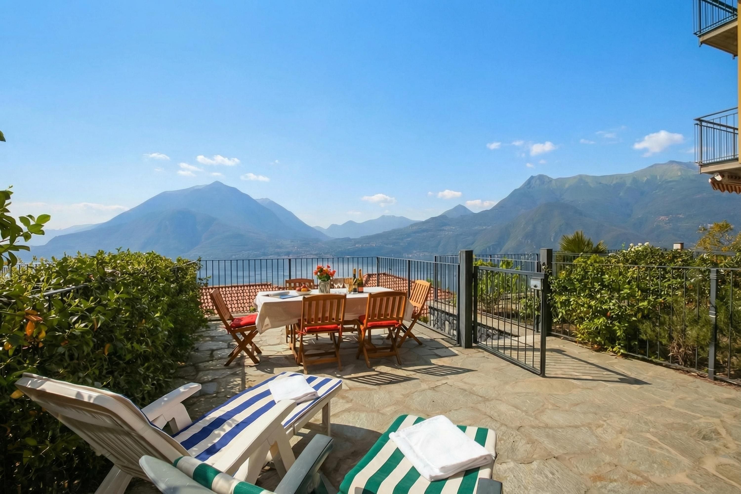 Une terrasse avec une table et des chaises, une vue sur les montagnes et des fauteuils de relaxation.