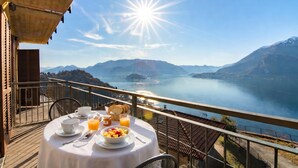 A table with breakfast items and a scenic view of a lake and mountains.
