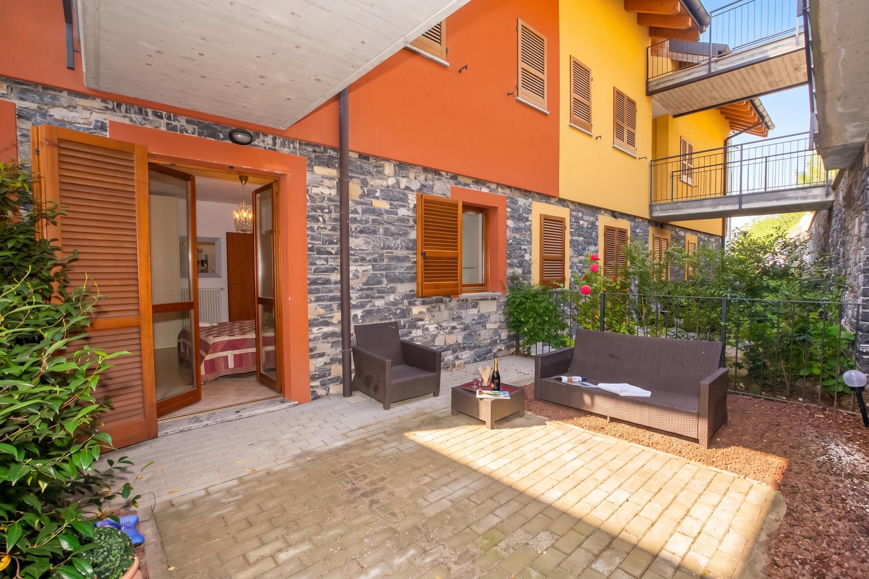 A courtyard with a sofa, chairs, and a table with drinks.