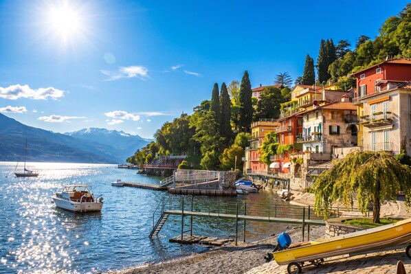 A lakeside town with boats docked, a dock, and buildings along the shore.
