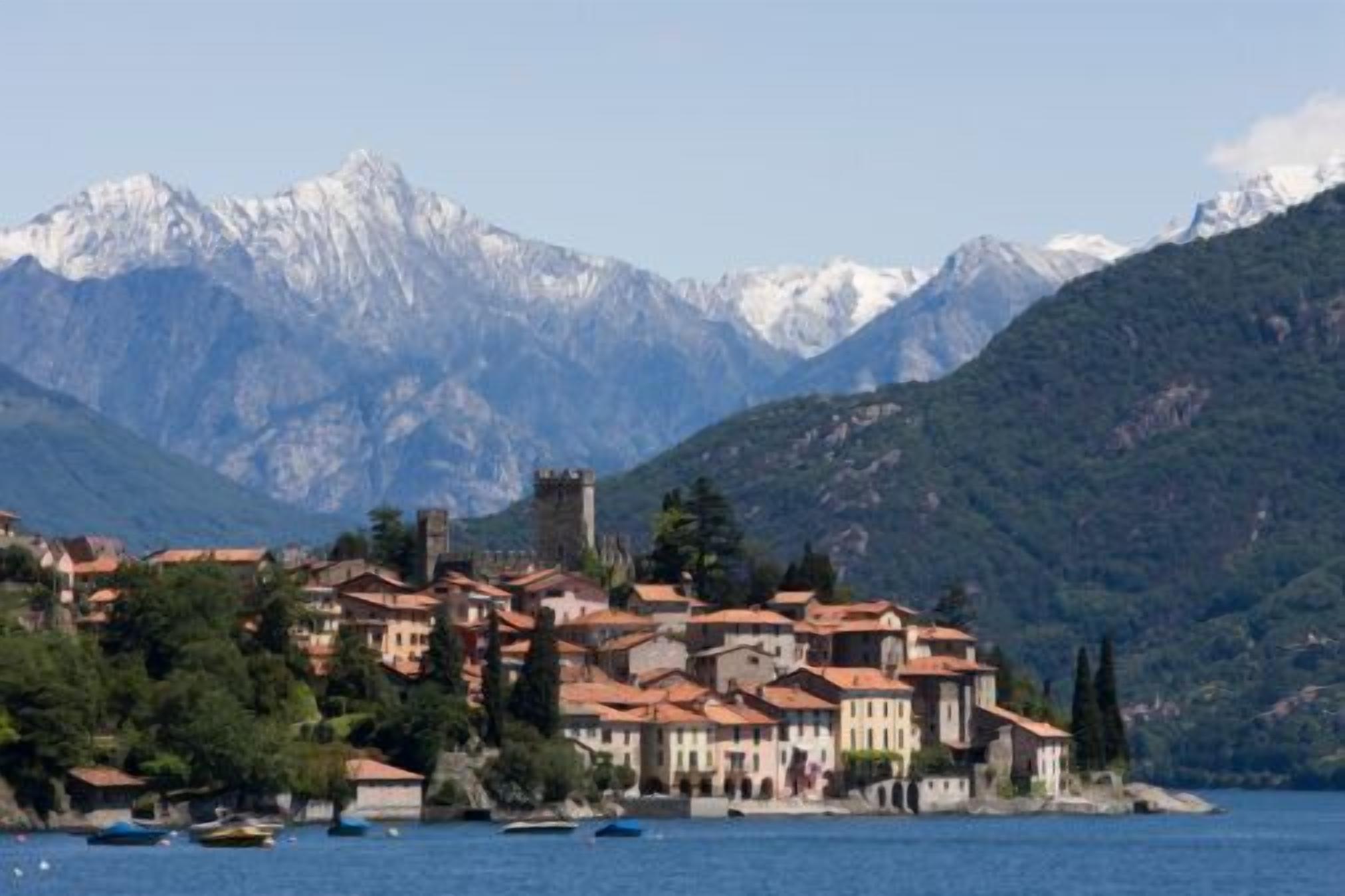 A coastal town with traditional architecture, a castle, and mountains in the background.