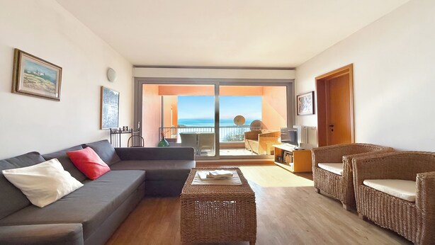 A living room with a grey sofa, wicker chairs, a coffee table, and a balcony with a view of the sea. - Gaeta Splendid Lake (San Siro)