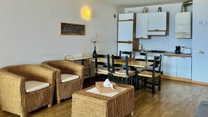 A cozy kitchen with wicker furniture, a dining table, and white cabinets. - Gaeta Splendid Lake (San Siro)