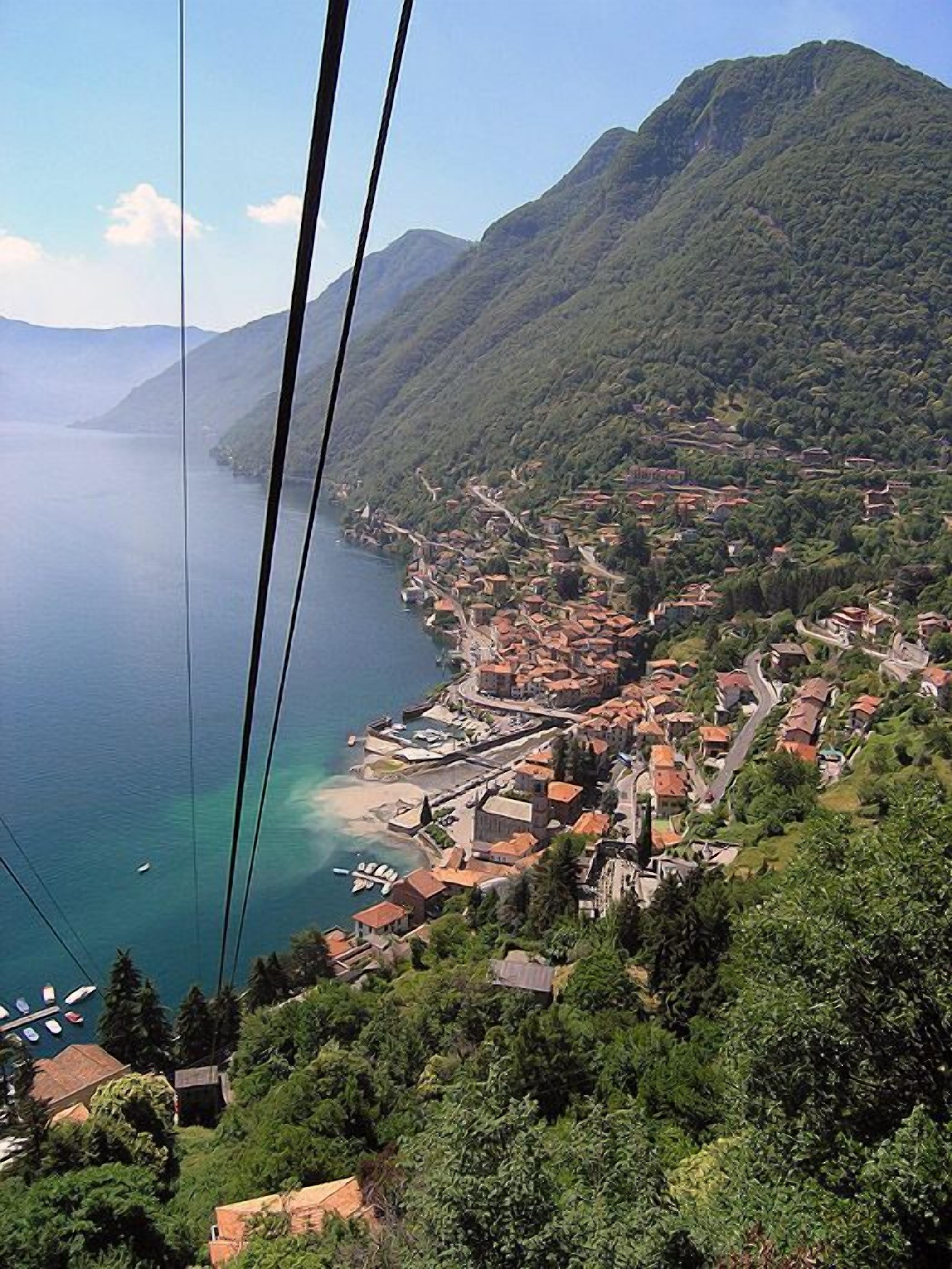 A coastal town with a mountainous backdrop, featuring a mix of residential buildings and a marina.