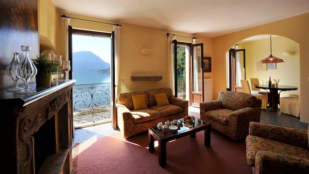 A living room with a sofa, armchairs, a coffee table, and a view of the sea. - La Piazza Porlezza (Porlezza)