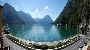 A lakeside view with mountains, a road, and a pedestrian path. - La Piazza Porlezza (Porlezza)