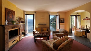 A cozy living room with a fireplace, comfortable seating, and large windows offering a scenic view. - La Piazza Porlezza (Porlezza)
