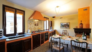 A kitchen with dark wooden cabinets, a granite countertop, a built-in oven, and a dining area with a table set for two. - La Piazza Porlezza (Porlezza)