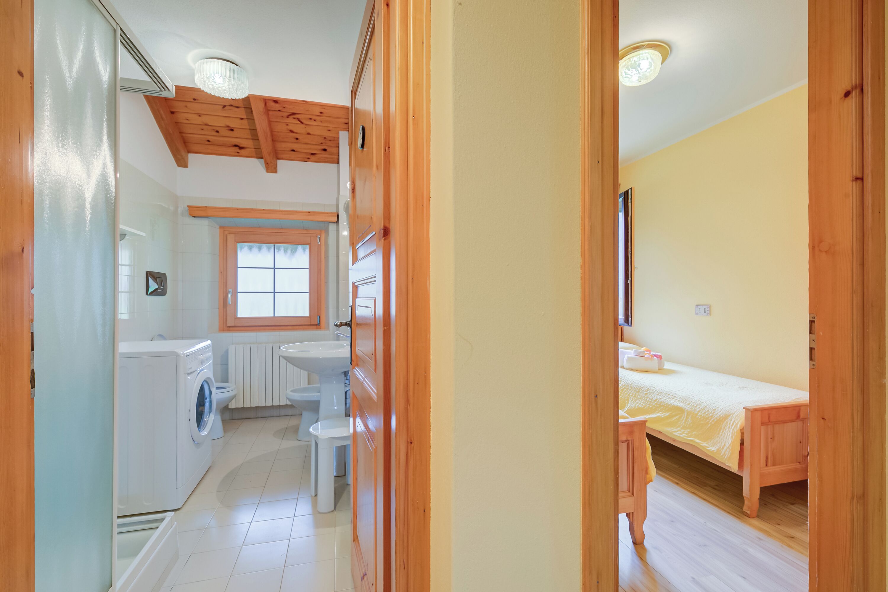 A compact room with a washing machine, sink, and a bed.