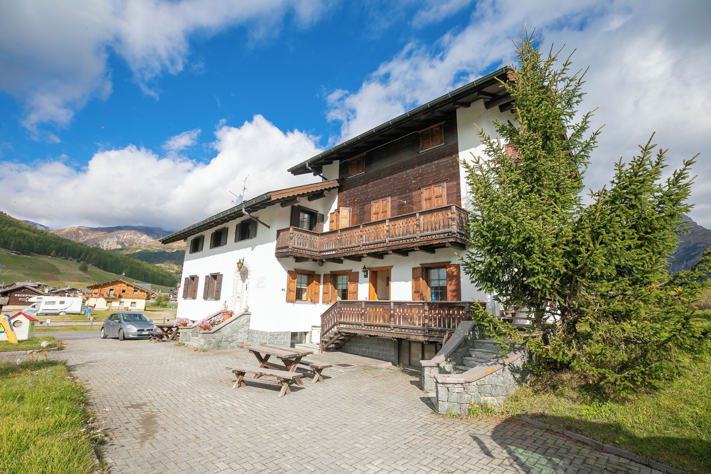 Un chalet traditionnel doté de balcons en bois, d’un escalier en pierre et d’une allée pavée.