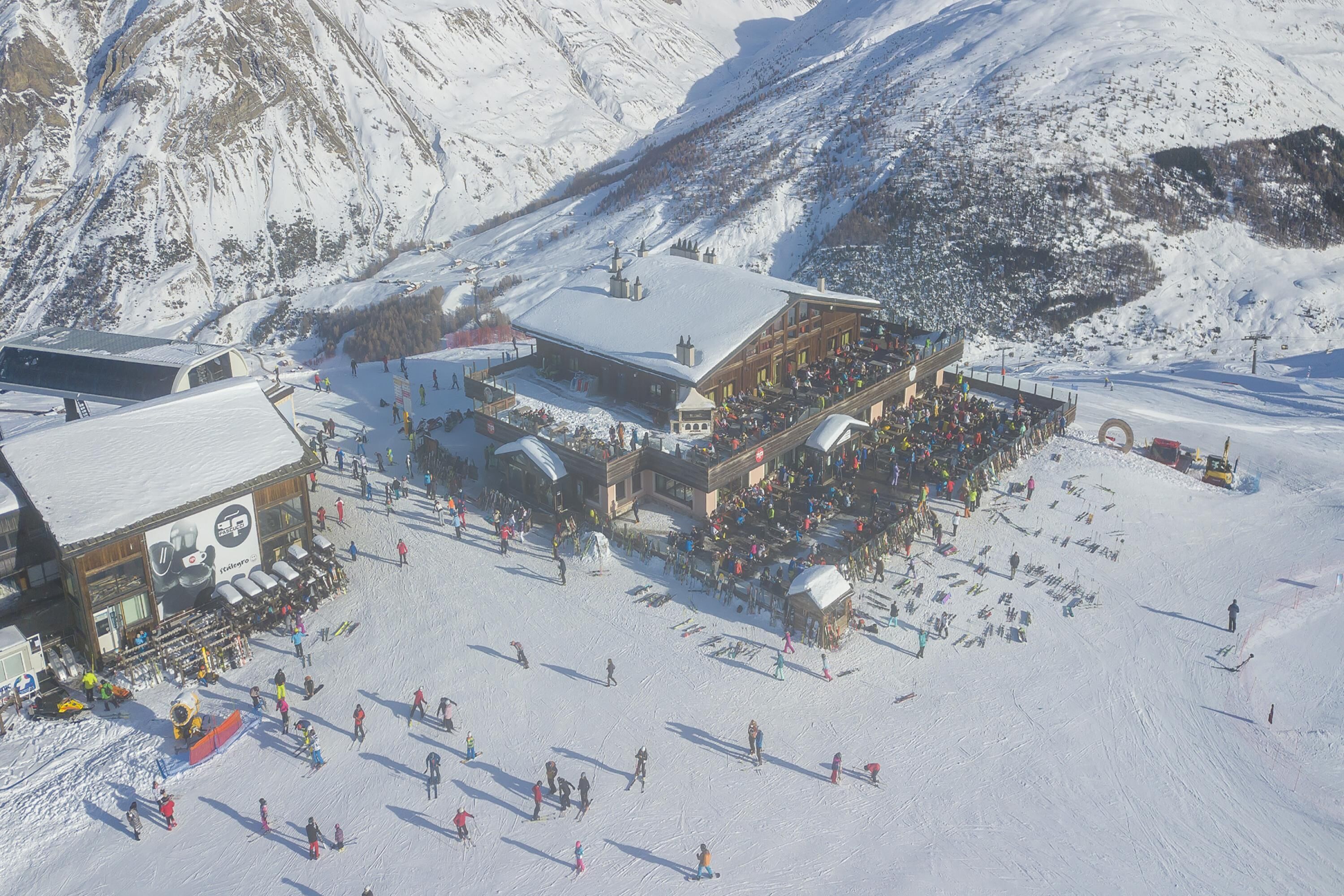 A ski resort with a large building, ski slopes, and a mountainous backdrop.