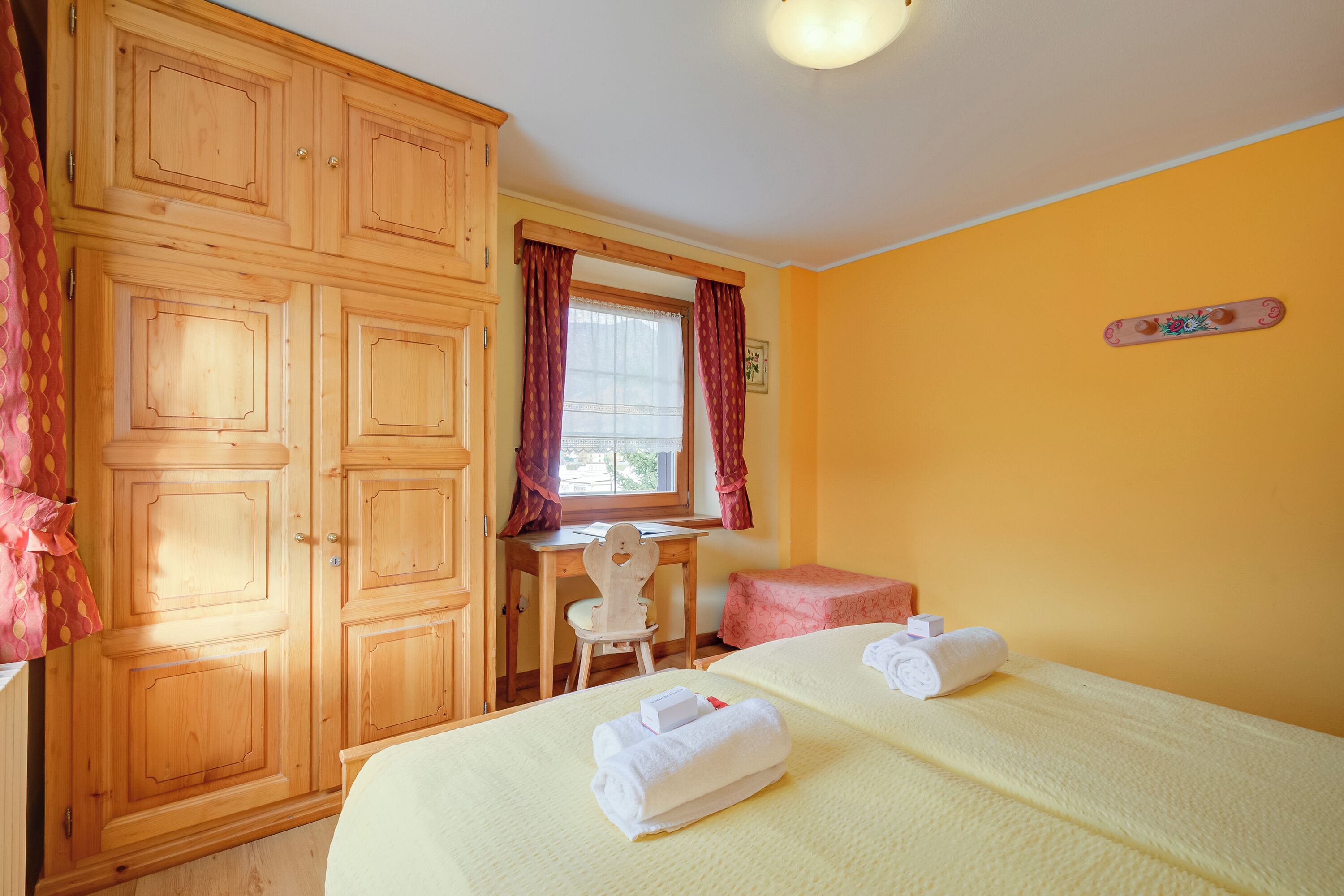Ein Hotelzimmer mit einem Bett, einem Schreibtisch, einem Stuhl und Holzschränken.