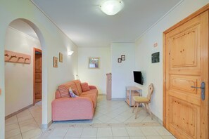 Une pièce comprenant un lit, un bureau, une chaise, un téléviseur et une porte en bois.