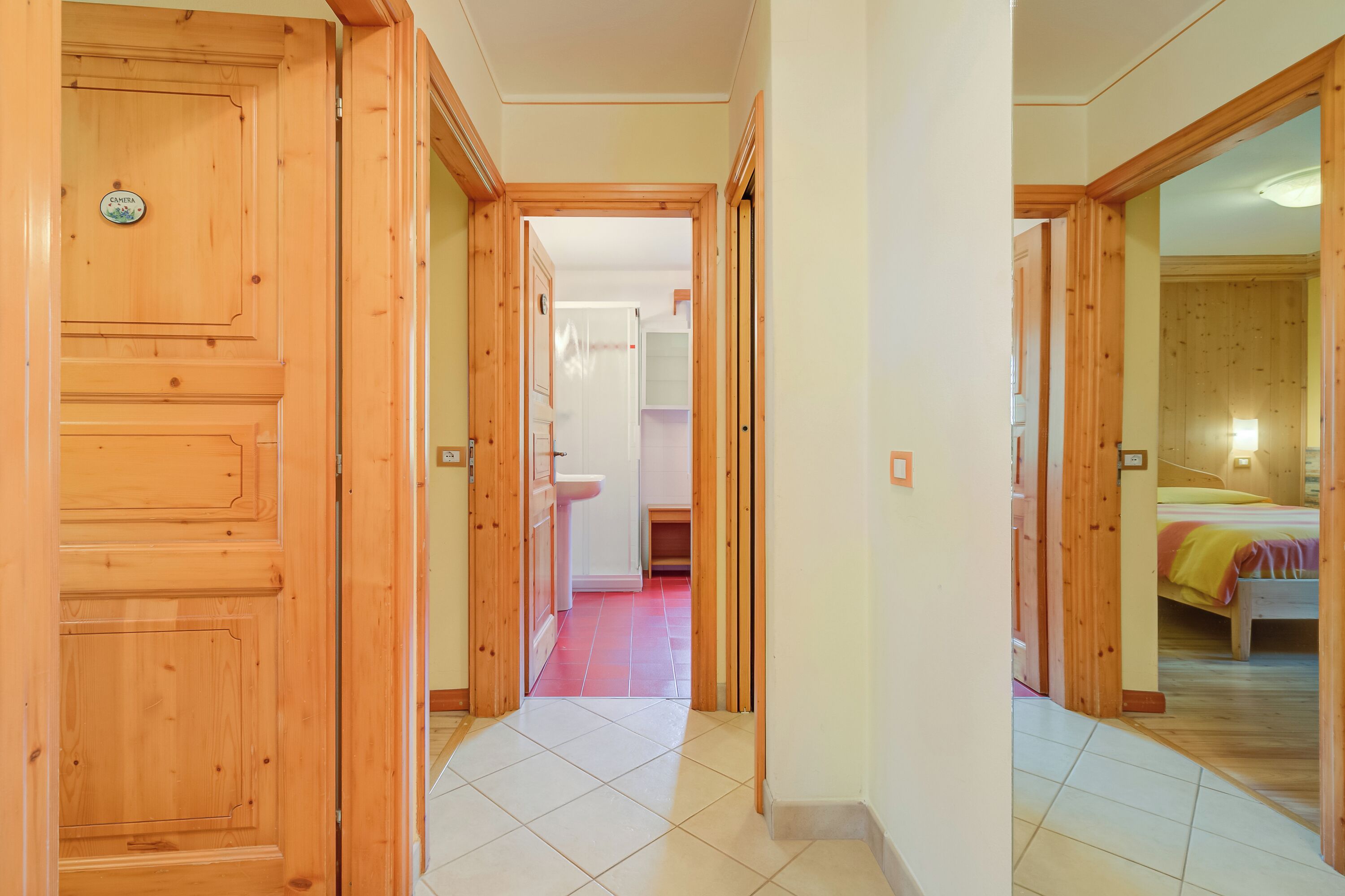 Een hal met houten deuren die leiden naar een badkamer en een slaapkamer.