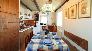 Un'area pranzo con un tavolo apparecchiato per sei persone, mobili contenitori in legno, un lampadario e stampe botaniche incorniciate alle pareti.