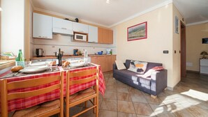 A compact living space with a dining area, kitchenette, and a sofa. - Italia 2 Ski in-Ski out 50m (Livigno)