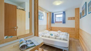 A room with a bed, a desk with a mirror, a wardrobe, and a window with curtains. - Italia 2 Ski in-Ski out 50m (Livigno)