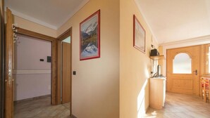 A hallway with wooden doors, a tiled floor, and framed pictures on the wall. - Italia 2 Ski in-Ski out 50m (Livigno)