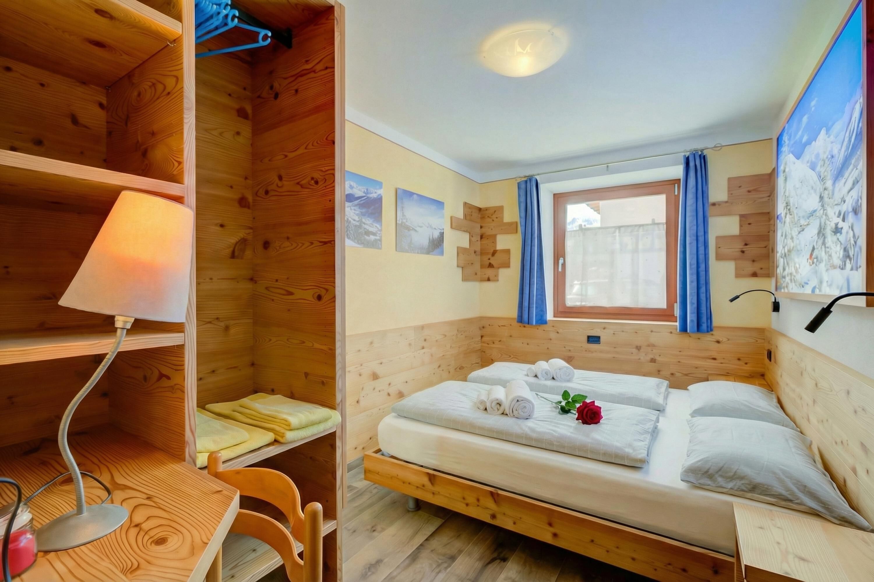 A wooden room with a bed, a desk, and a chair.