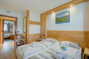 A bedroom with two beds, wooden headboard, a painting, and a wooden desk.