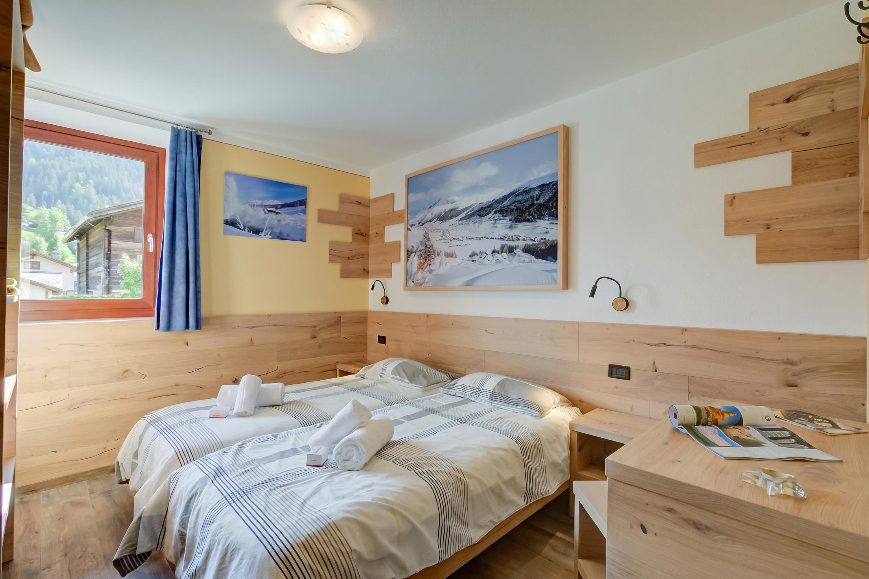 A wooden-paneled bedroom with a bed, two wall-mounted lights, and a window with a curtain.