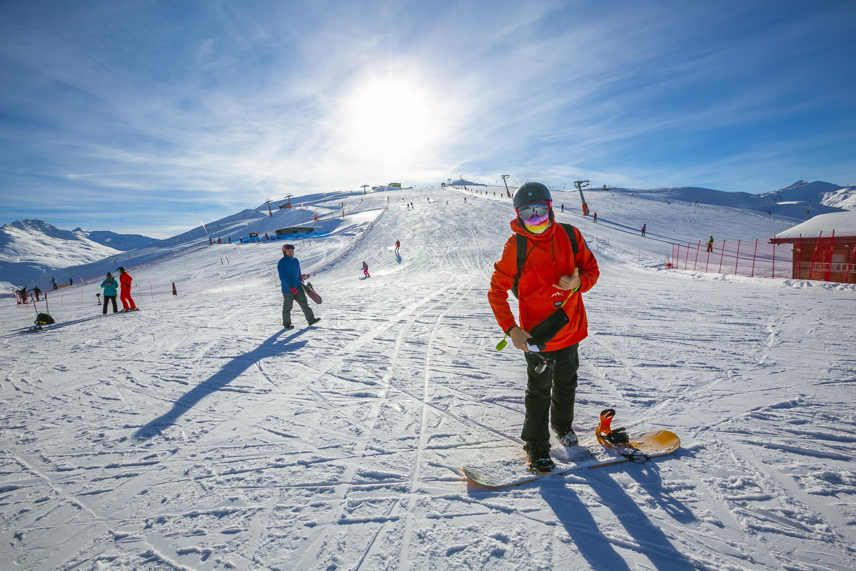 Ein verschneiter Skipisten mit Skifahrern und Snowboardern.