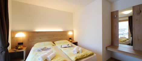 Une chambre d’hôtel avec deux lits, des lampes de chevet, un miroir et une fenêtre.