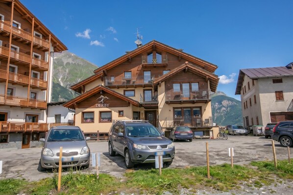 A hotel with a wooden facade, balconies, and a mountain backdrop.