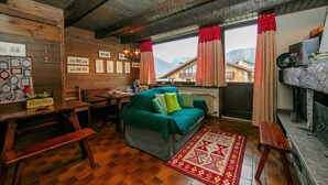 Une pièce chaleureuse avec un plafond en bois, un canapé vert, une table en bois et une cheminée.