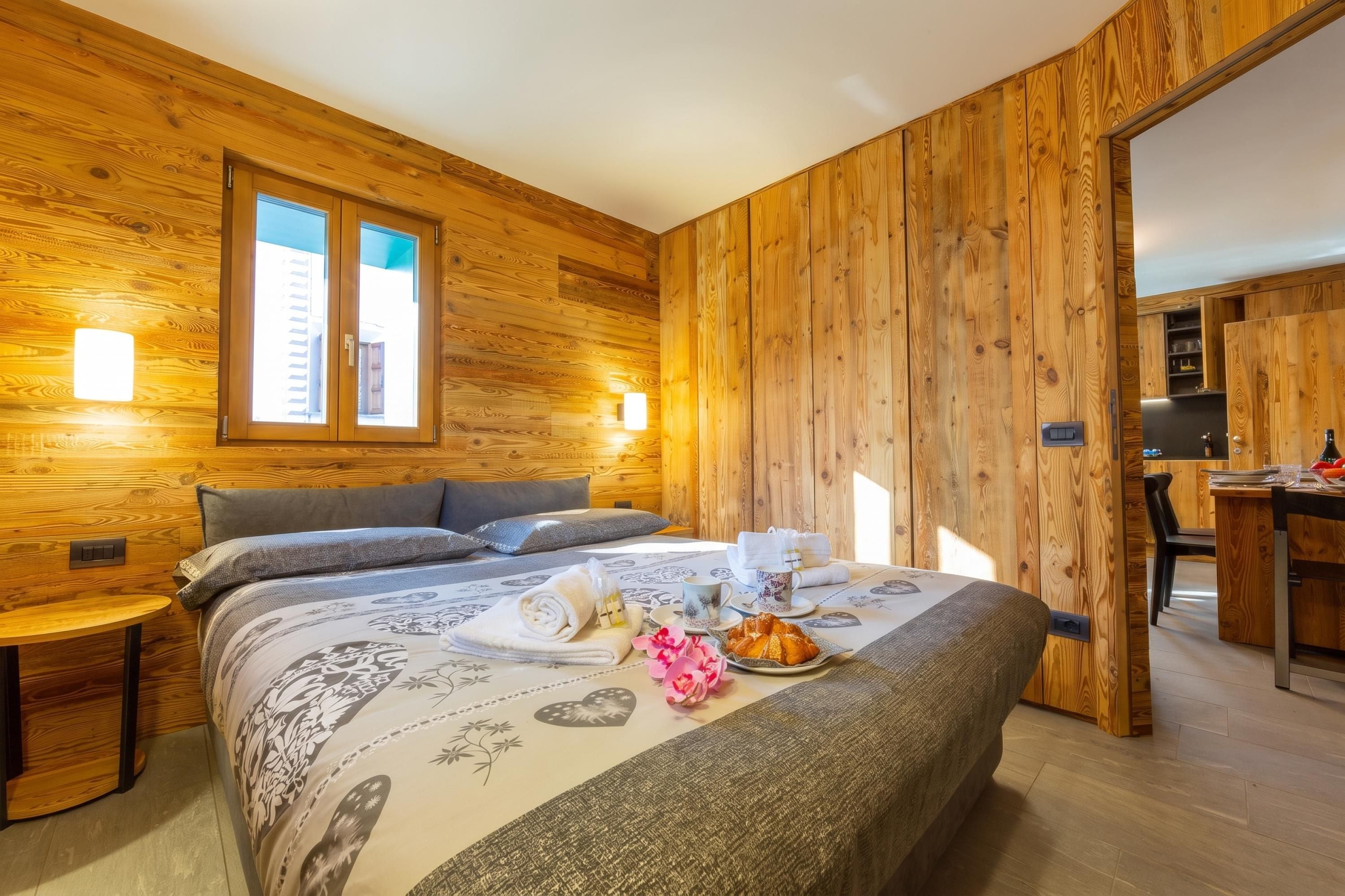 A wooden-paneled room with a bed, bedside tables, and a window.