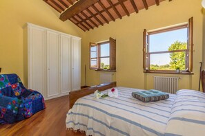 Un dormitorio con cama, una silla, un armario y una ventana con vistas.
