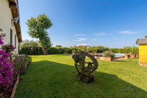 Un jardín bien cuidado con césped, un árbol grande y una piscina.